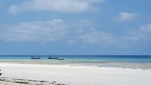 View of boats in calm sea against cloudy sky