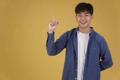 Portrait of smiling man standing against yellow background