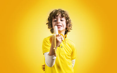 Portrait of smiling young woman against yellow background