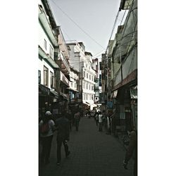 People walking on street amidst buildings in city