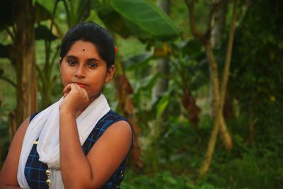 Portrait of beautiful young woman standing against plants