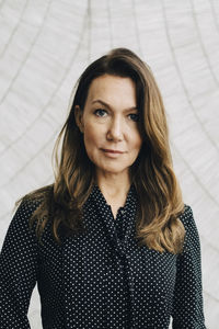 Portrait of smiling businesswoman against wall at office