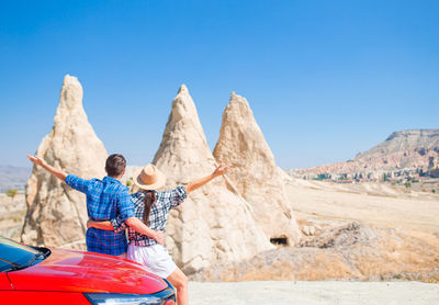 Rear view of woman sitting on mountain against clear blue sky