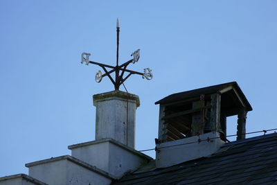 Low angle view of weather vane against blue sky