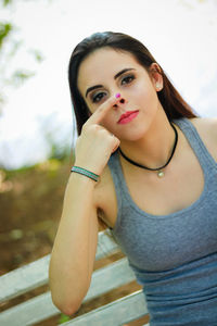 Portrait of young woman touching her nose at park