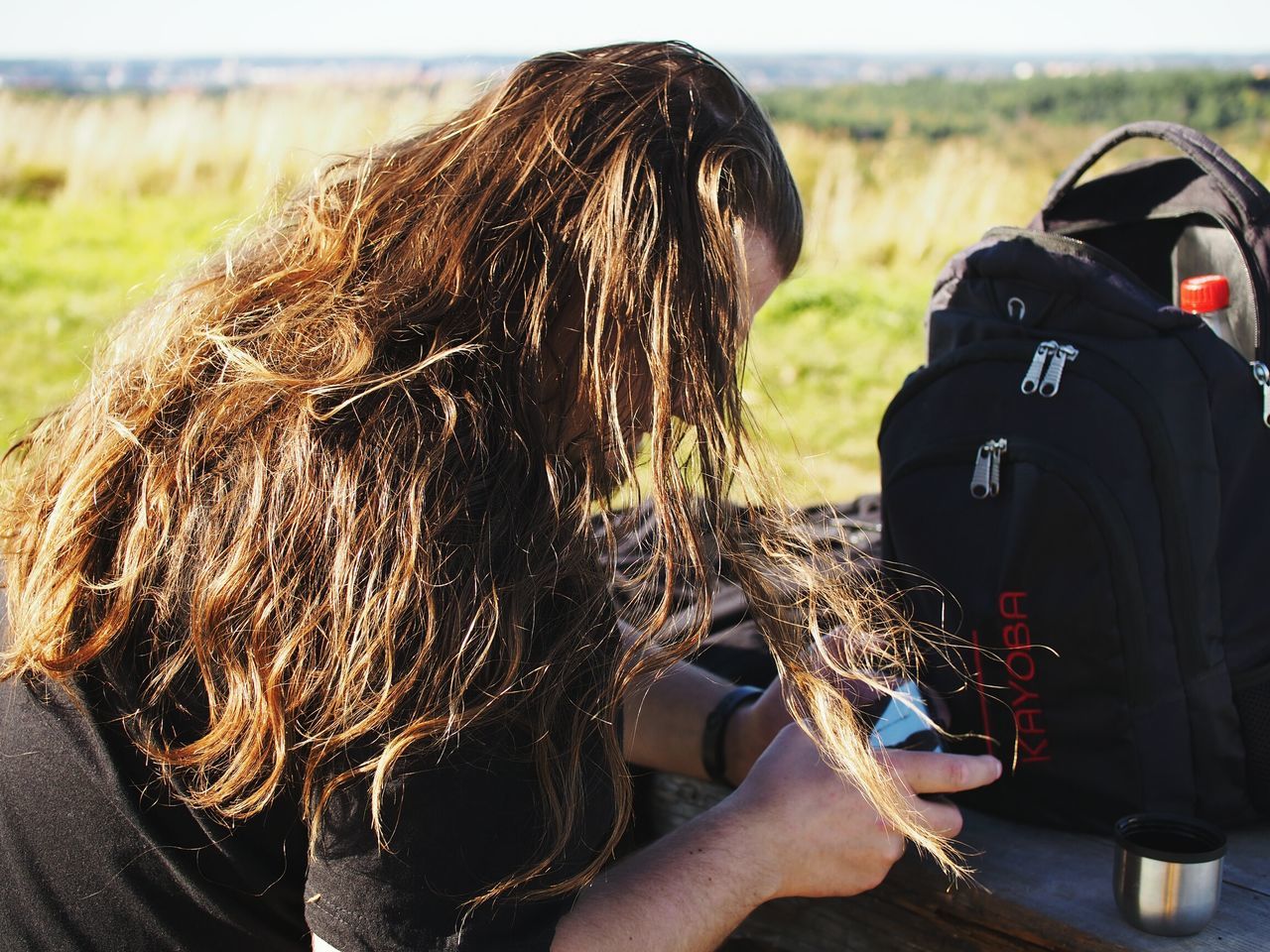 focus on foreground, lifestyles, leisure activity, person, rear view, holding, long hair, beach, outdoors, day, close-up, men, part of, casual clothing, headshot, sitting