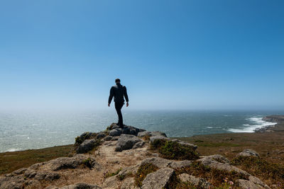 Lone person walking on rocks on headlands over looking pacific ocean