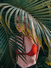 Woman standing by palm leaves