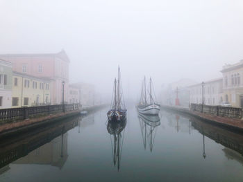 Boats in canal amidst city against sky