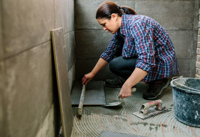 Side view of man working against wall