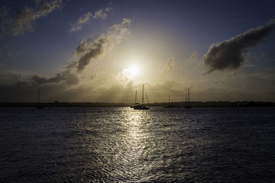 Silhouette sailboats in sea against sky during sunset