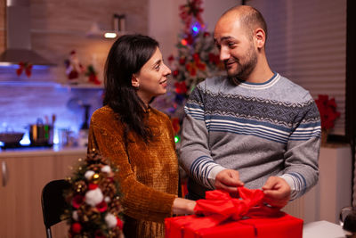 Smiling couple holding gift at home