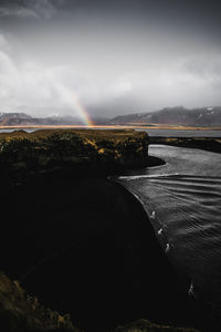 Scenic view of rainbow over river against sky