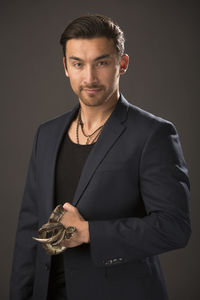 Close-up portrait of male model with snake against brown background