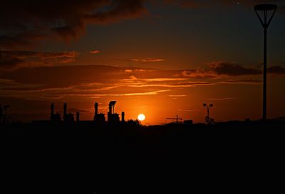 Silhouette landscape against orange sky