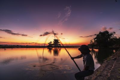 Man standing on lake against sky during sunset