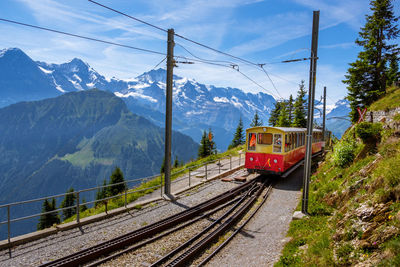 Train on railroad track by mountain against sky