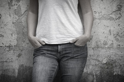 Midsection of woman standing against weathered wall