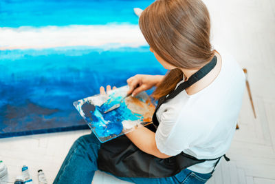 High angle view of woman painting on canvas