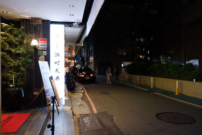 Vehicles on road along buildings at night