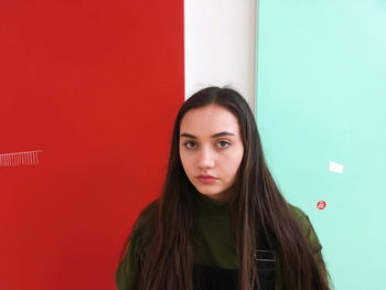 Portrait of beautiful young woman standing by wall