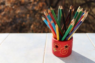 Close-up of colored pencils in desk organizer on table