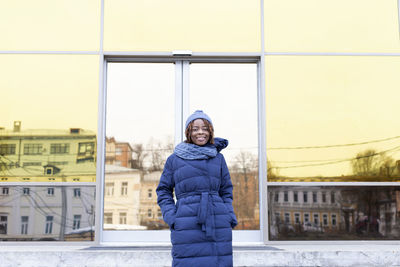 Portrait of woman standing by entrance of building