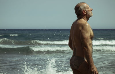 Adult man in swimwear against sea and sky