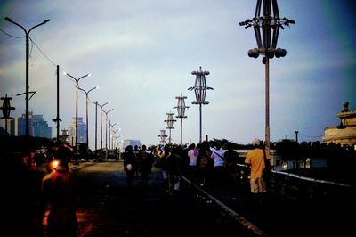 People walking on street in city against sky