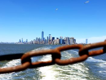 Sea by modern buildings against clear blue sky