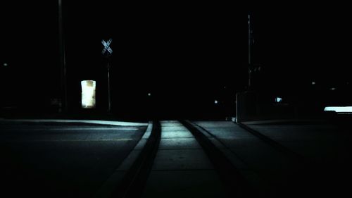 Illuminated street lights on footpath by building at night