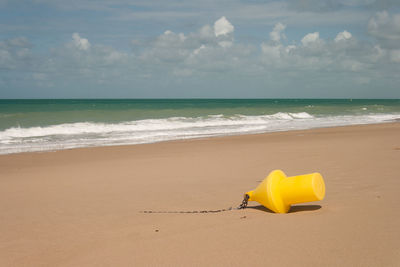 Yellow umbrella on beach against sky