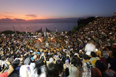 Group of people at music concert against sky during sunset