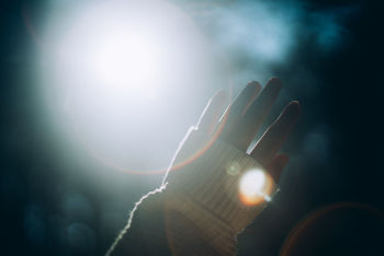 Close-up of hand against sky during sunny day