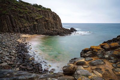 Scenic view of sea by cliff against sky