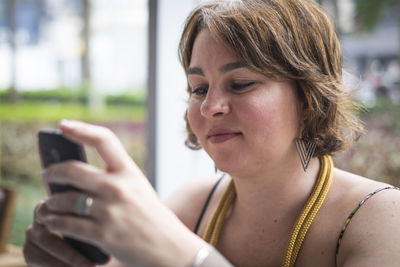 Close-up of woman using smart phone while sitting outdoors