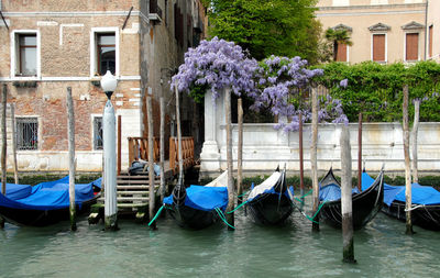 Boats moored in canal by buildings in city