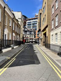 Empty road by buildings in city