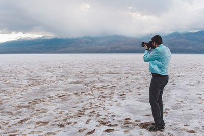 Side view man photographing through camera while standing at death valley national park