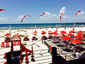 Red parasols at beach against sky