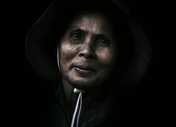 Portrait of young woman against black background