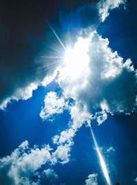 Low angle view of sunlight streaming through clouds