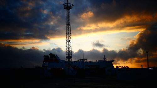 Silhouette cranes against sky during sunset