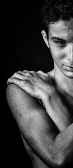 Portrait of shirtless man against black background