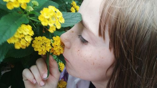 Close-up of girl smelling yellow flowers