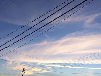 Low angle view of electricity pylon against cloudy sky