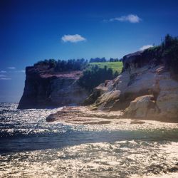 Scenic view of rocky beach against blue sky