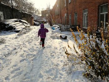 Rear view of person walking on snow covered street during winter