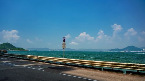 Road by sea against blue sky