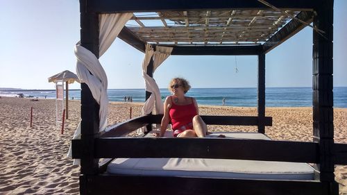 Rear view of woman sitting at beach